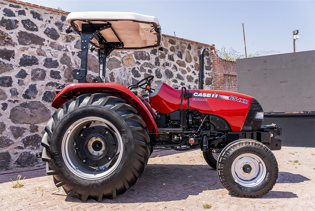 Tractor multiusos Case IH 65JXM estacionado junto a un muro de piedra