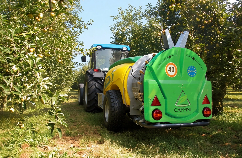 Atomizador agrícola Caffini con alerones plegados acoplado a tractor en campo de cultivo