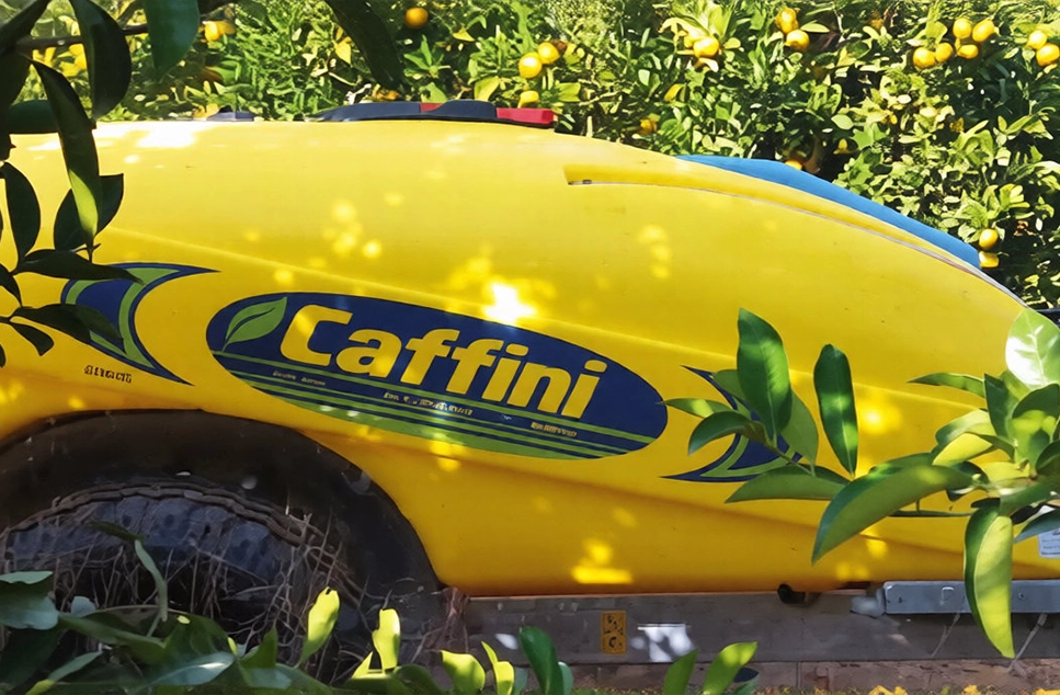 Tanque de polietileno amarillo de atomizador de arrastre Caffini en huerto de cítricos