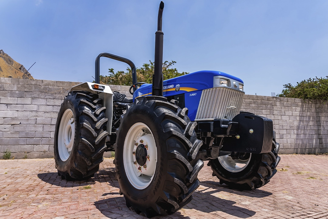 Tractor agrícola New Holland 6610S Herencia 4WD estacionado en exterior con contrapesos delanteros