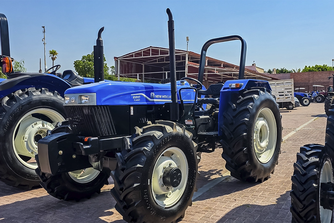Vista tres cuartos frontal del tractor New Holland 6810 Turbo exhibido en un patio exterior.