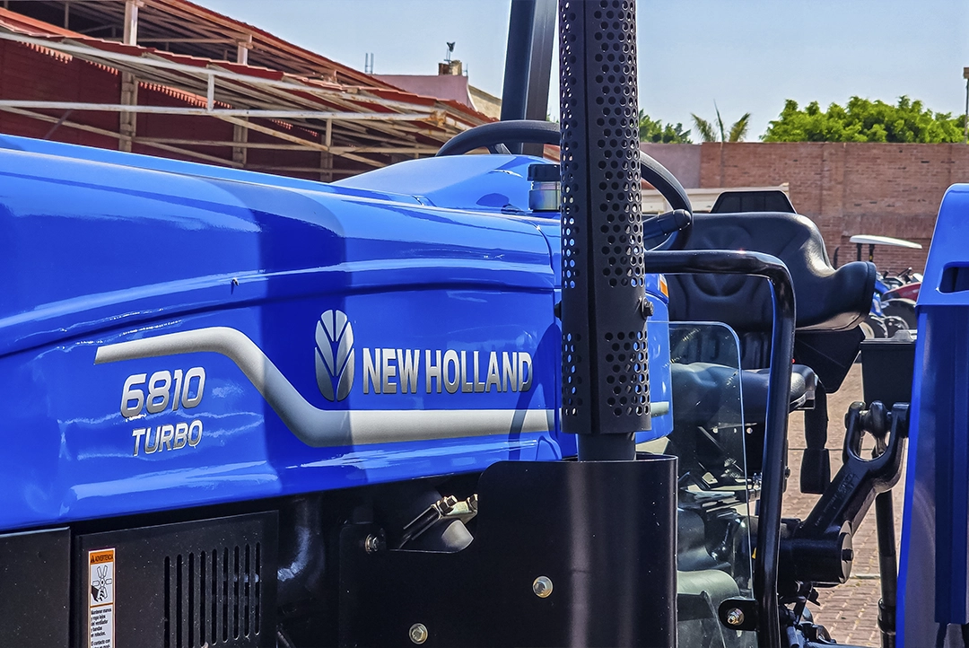 Detalle del cofre azul con la insignia New Holland 6810 Turbo y el puesto del operador.