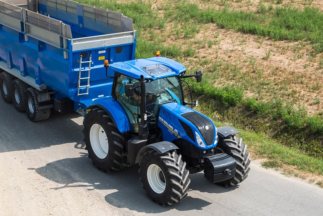 Vista aérea de un tractor New Holland T7 245 arrastrando un remolque de carga agrícola azul en camin