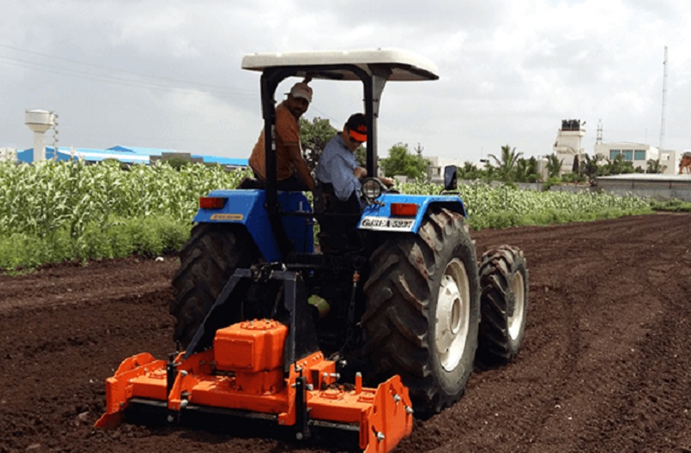 Tractor agrícola con grada rotativa de color naranja en el campo